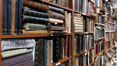 Obrazek przedstawia wnętrze biblioteki, w której półki są wypełnione starymi książkami, ułożonymi ciasno na regałach.