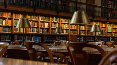 Obrazek przedstawia wnętrze starej biblioteki, na pierwszym planie stół, na drugim regały z książkami.